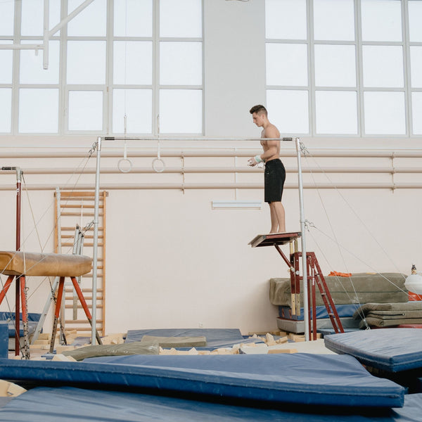 Man on balance beam with blue crash mats Canada